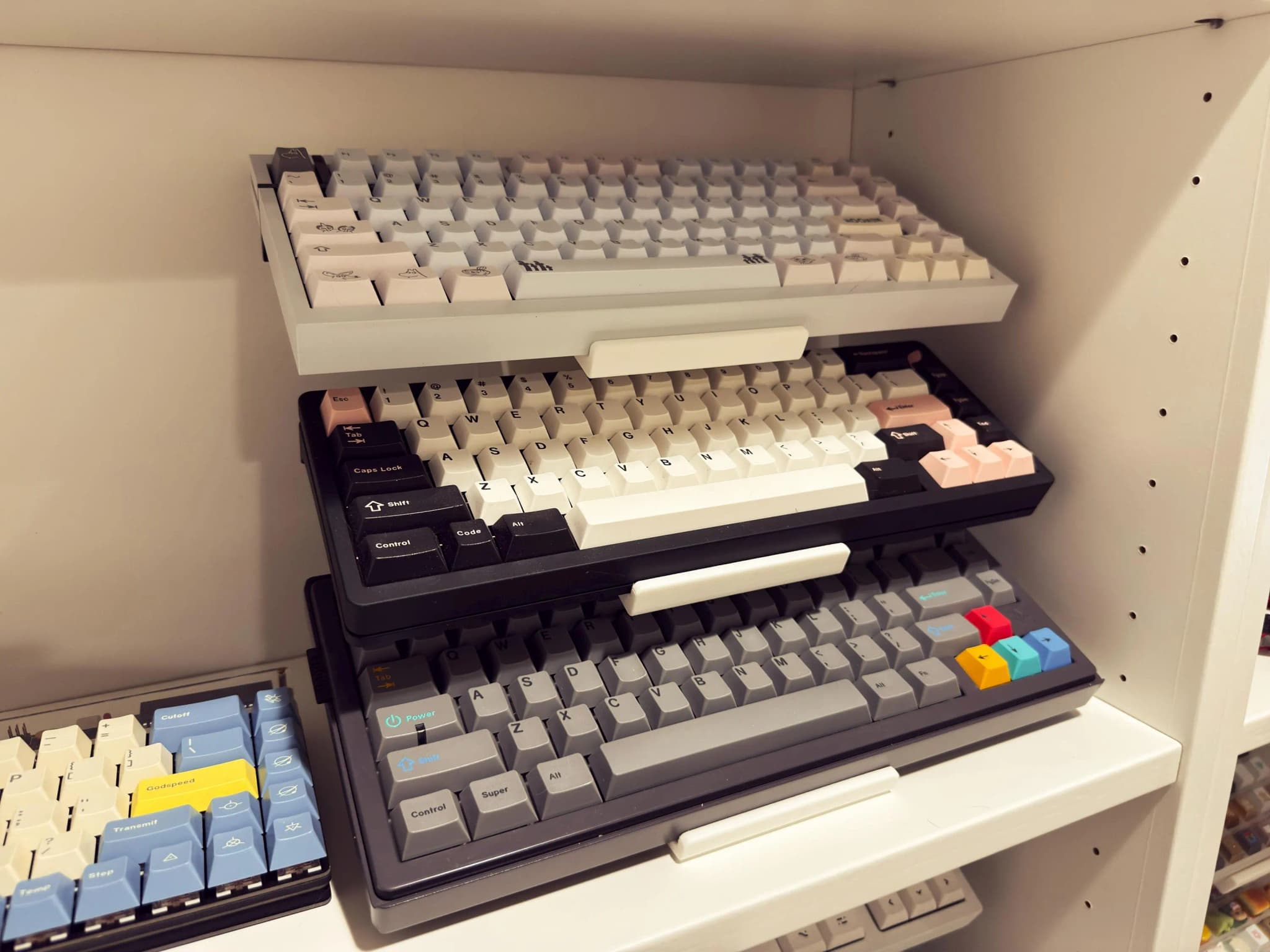 Three keyboards on a black stand inside a shelving unit